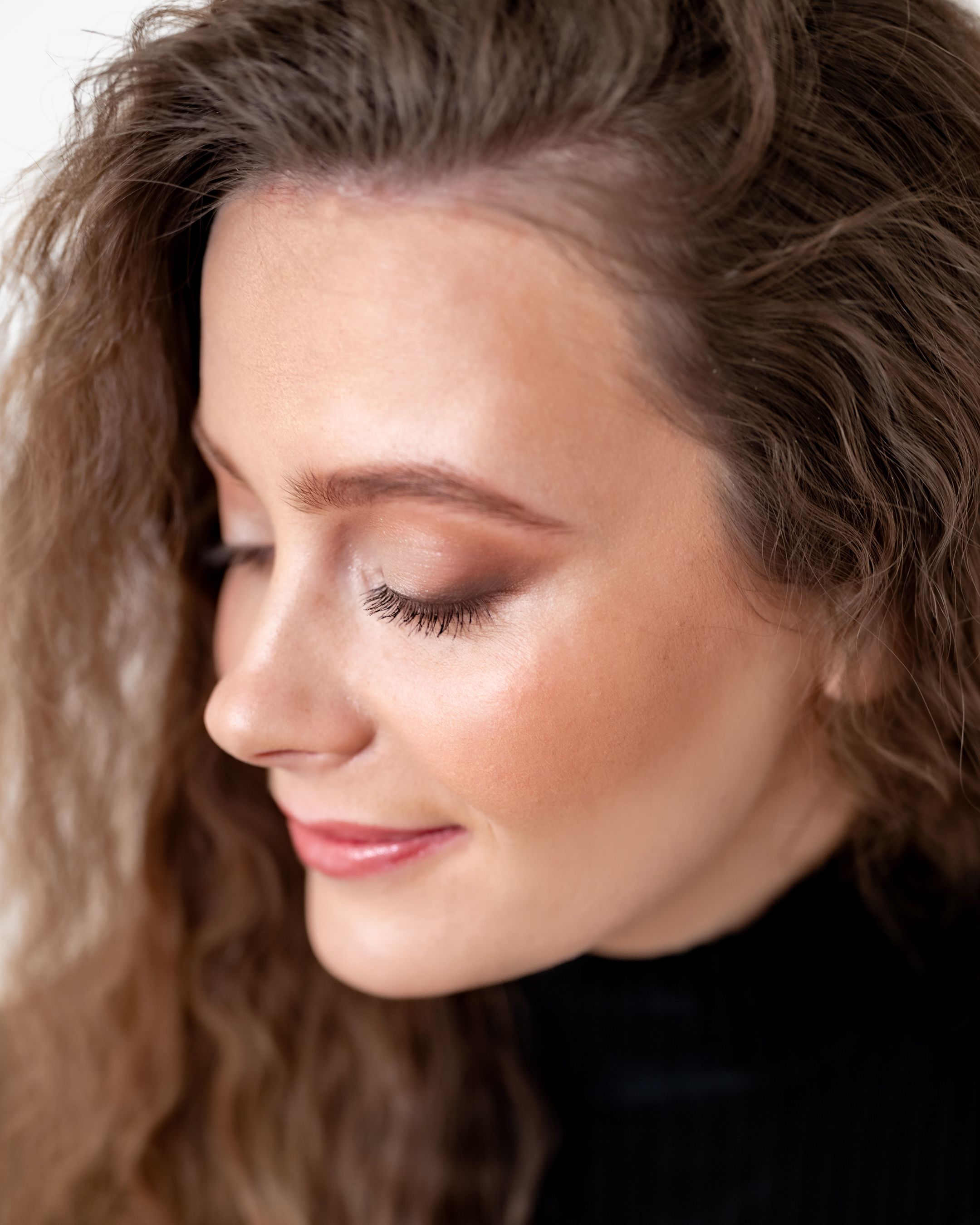 Side profile beauty shot showcasing natural makeup and textured hair.