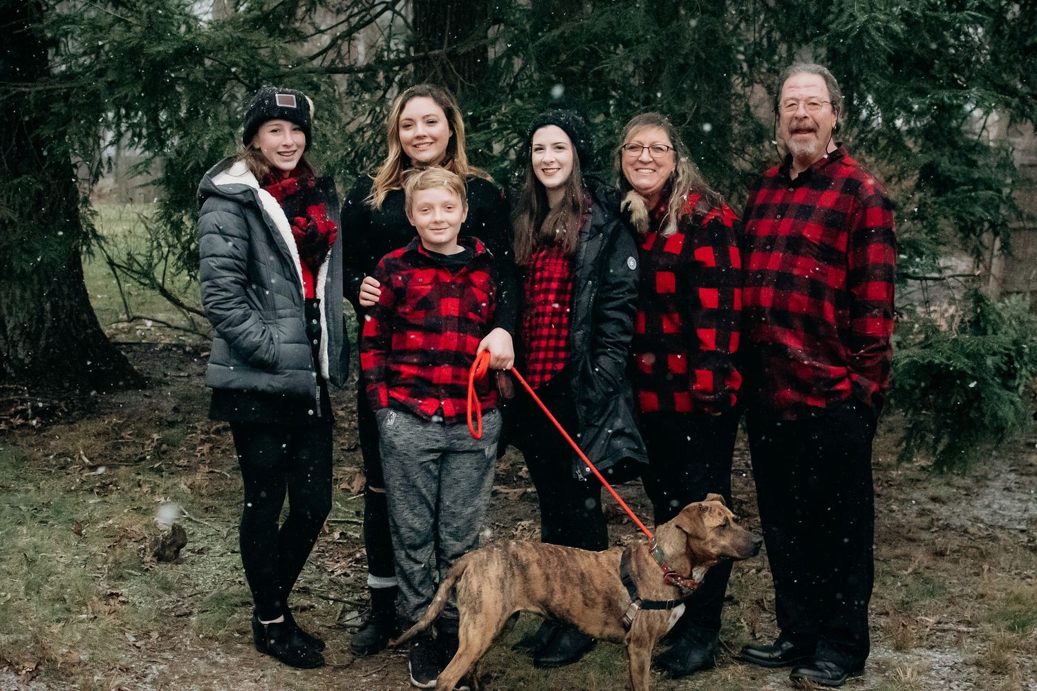 family posing in falling snow for winter Christmas portrait