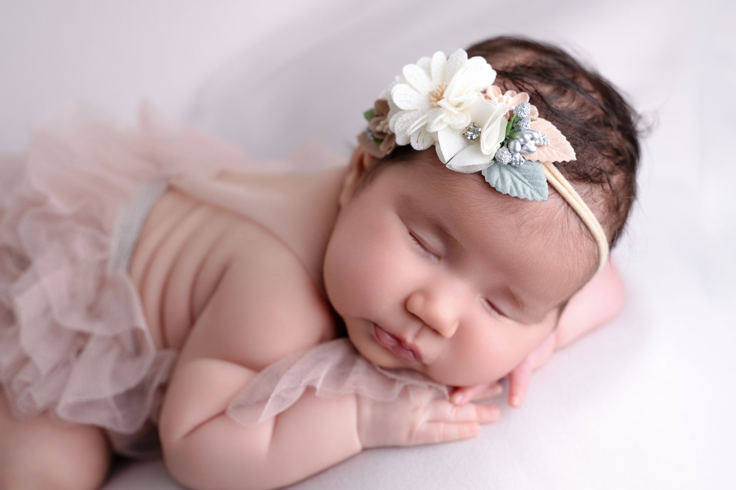 Sleeping newborn baby girl wearing a tutu and white floral headband in a soft dreamy portrait. baby milestone - cypress newborn photography