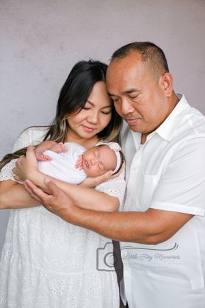 Parents tenderly hold their swaddled newborn baby during a professional studio portrait session. natural newborn photography