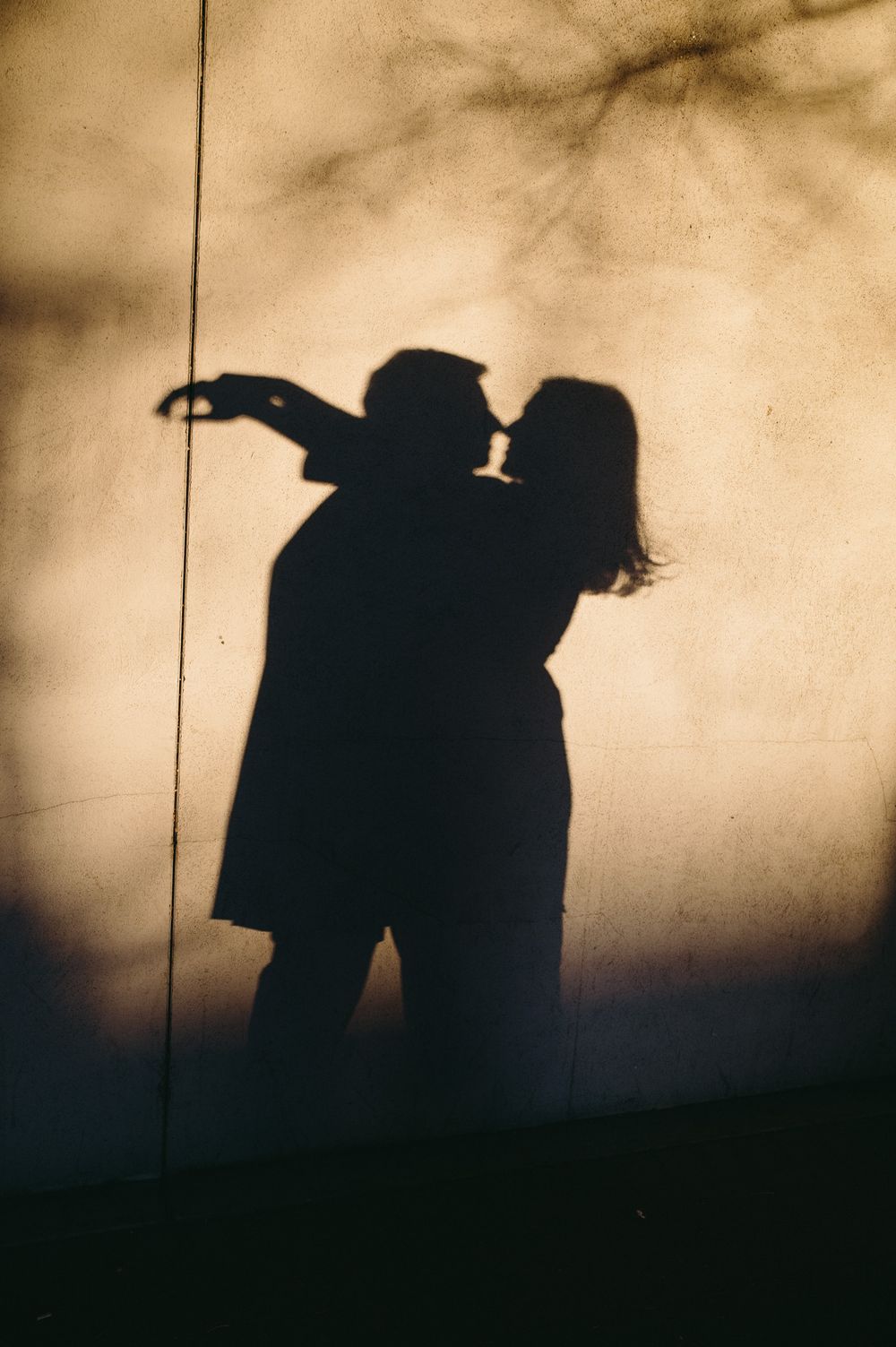Silhouettes of two figures walking together at sunset create a romantic atmospheric scene against a sepia-toned sky.