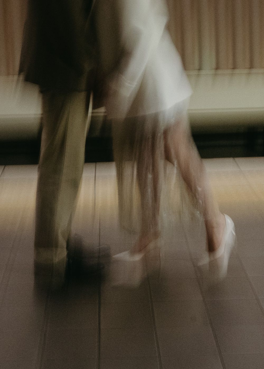 Blurred motion of a person walking on a light colored floor, creating an ethereal ghostly effect.