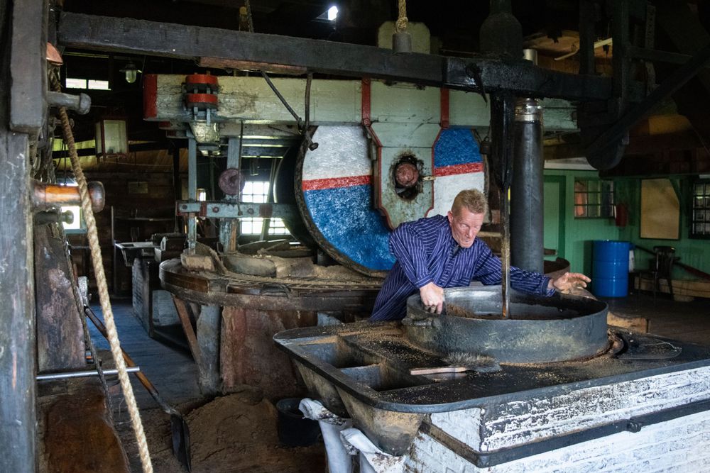 Person working at an old mill control station with vintage equipment and gauges.