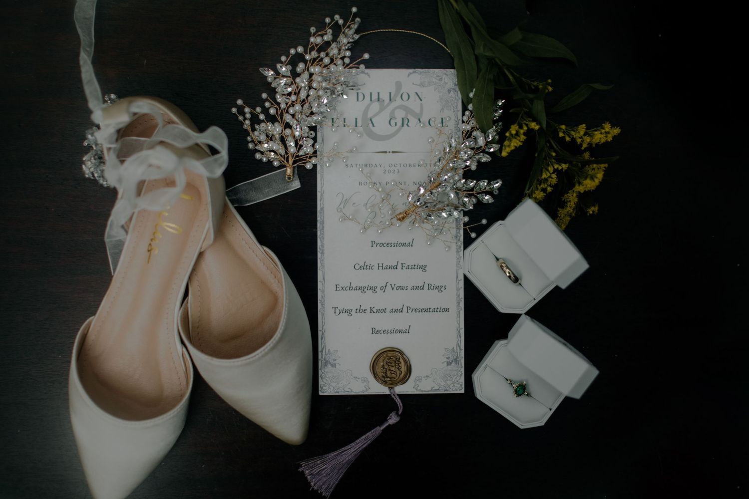 Wedding invitation and delicate pink ballet flats arranged artistically on dark background.