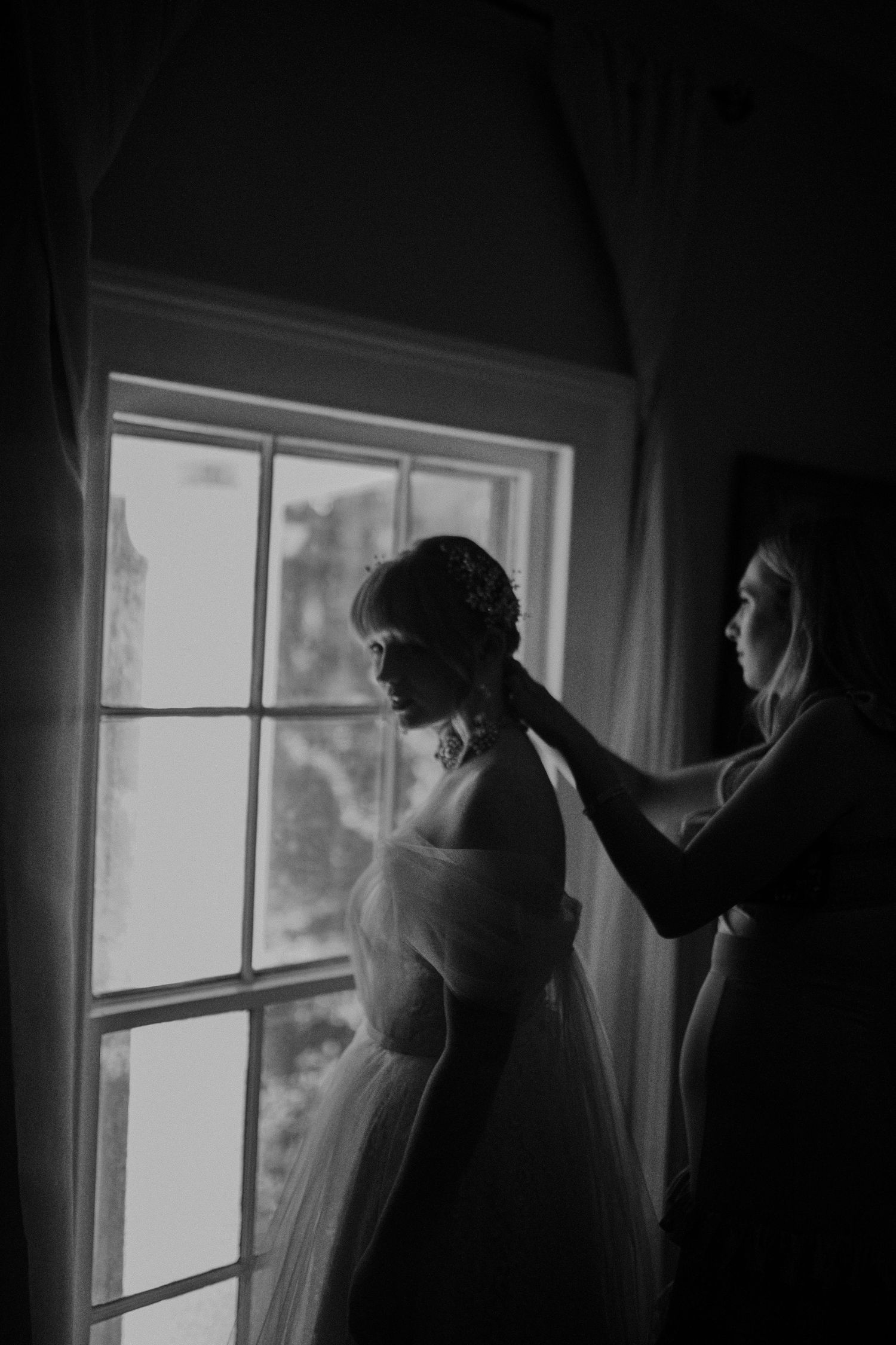 Silhouetted figures dance in front of bright windows creating a dramatic wedding moment.
