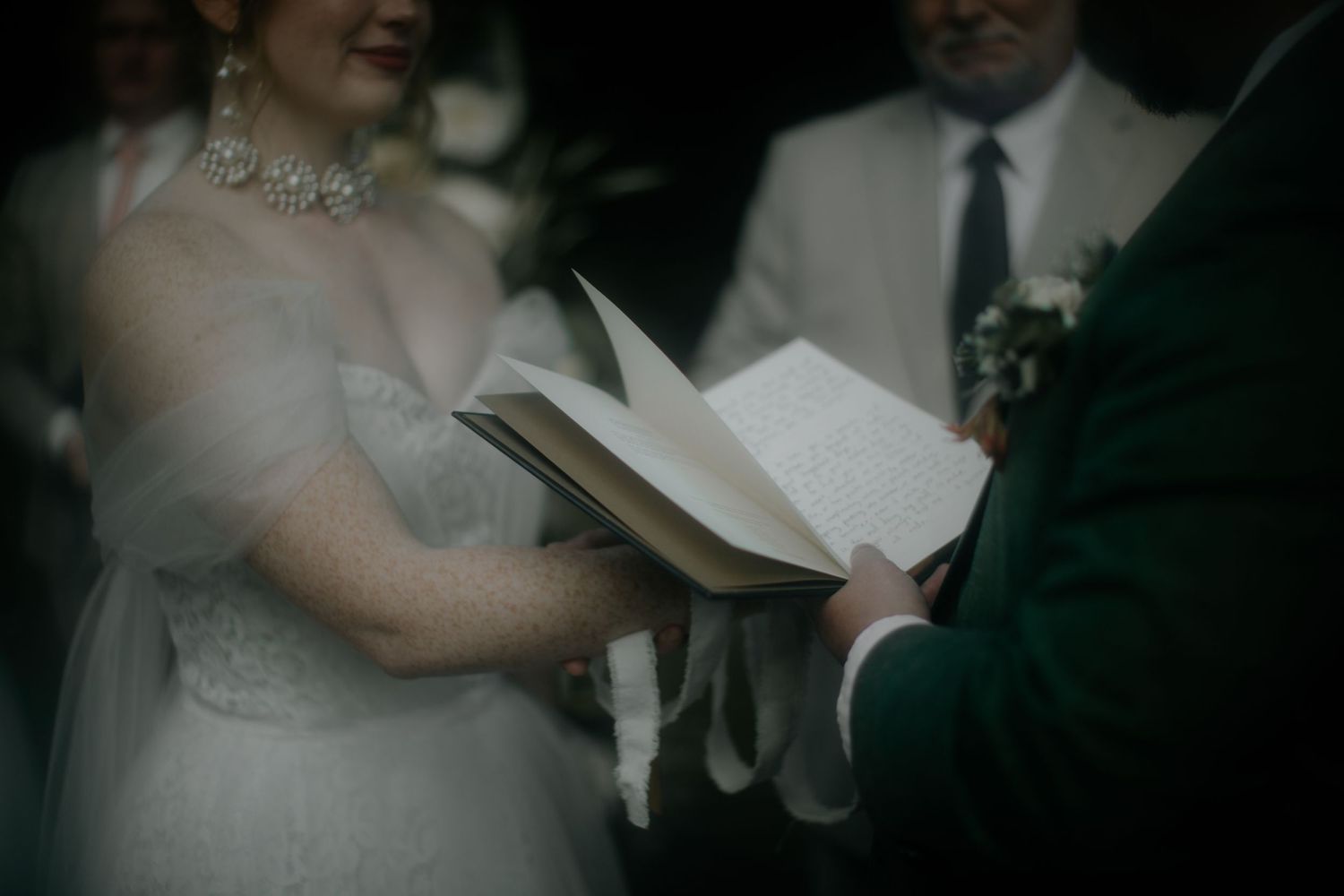Emotional wedding ceremony moment as vows are exchanged in dim lighting.