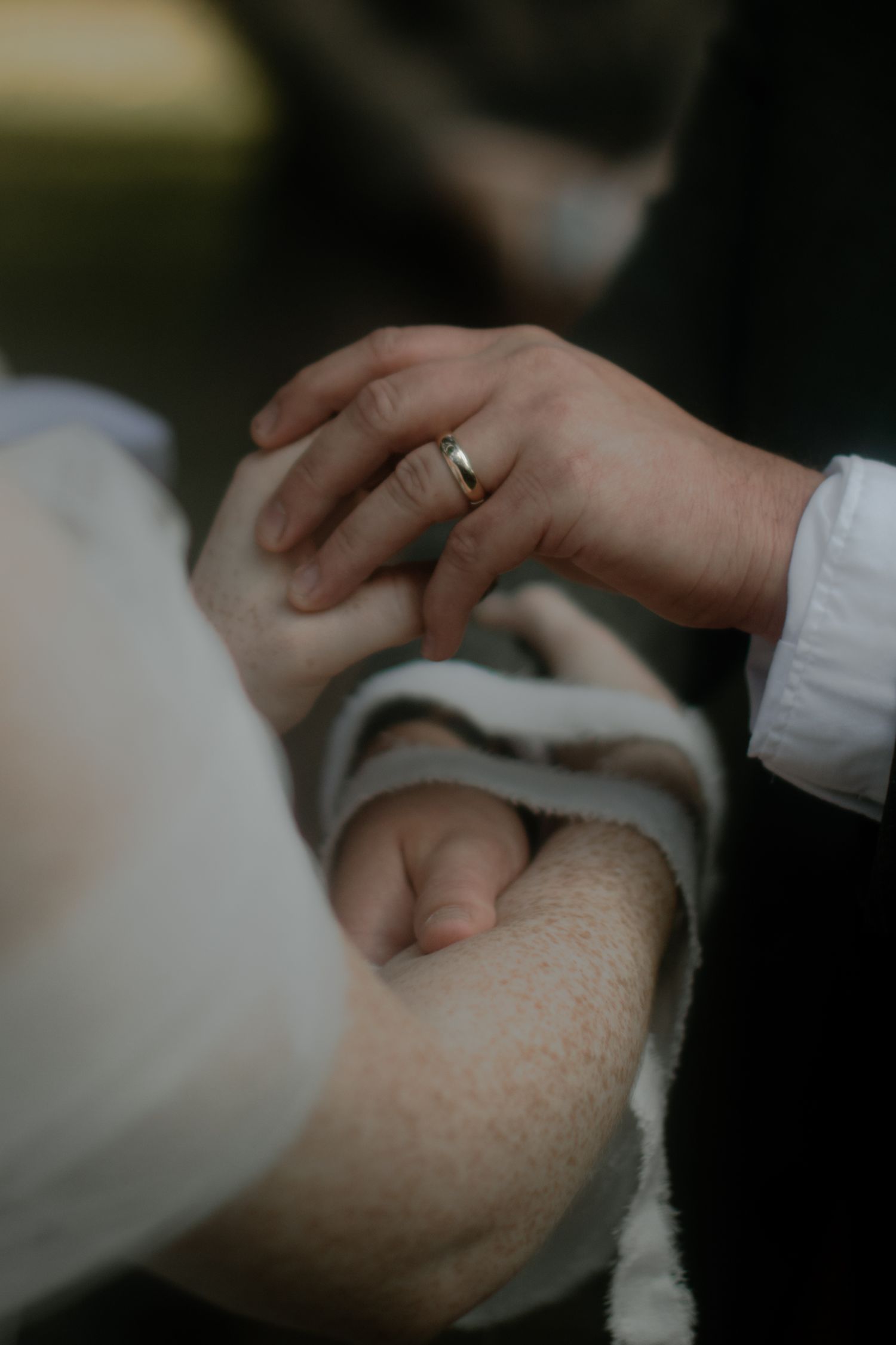 Close-up of hands exchanging wedding rings during ceremony.