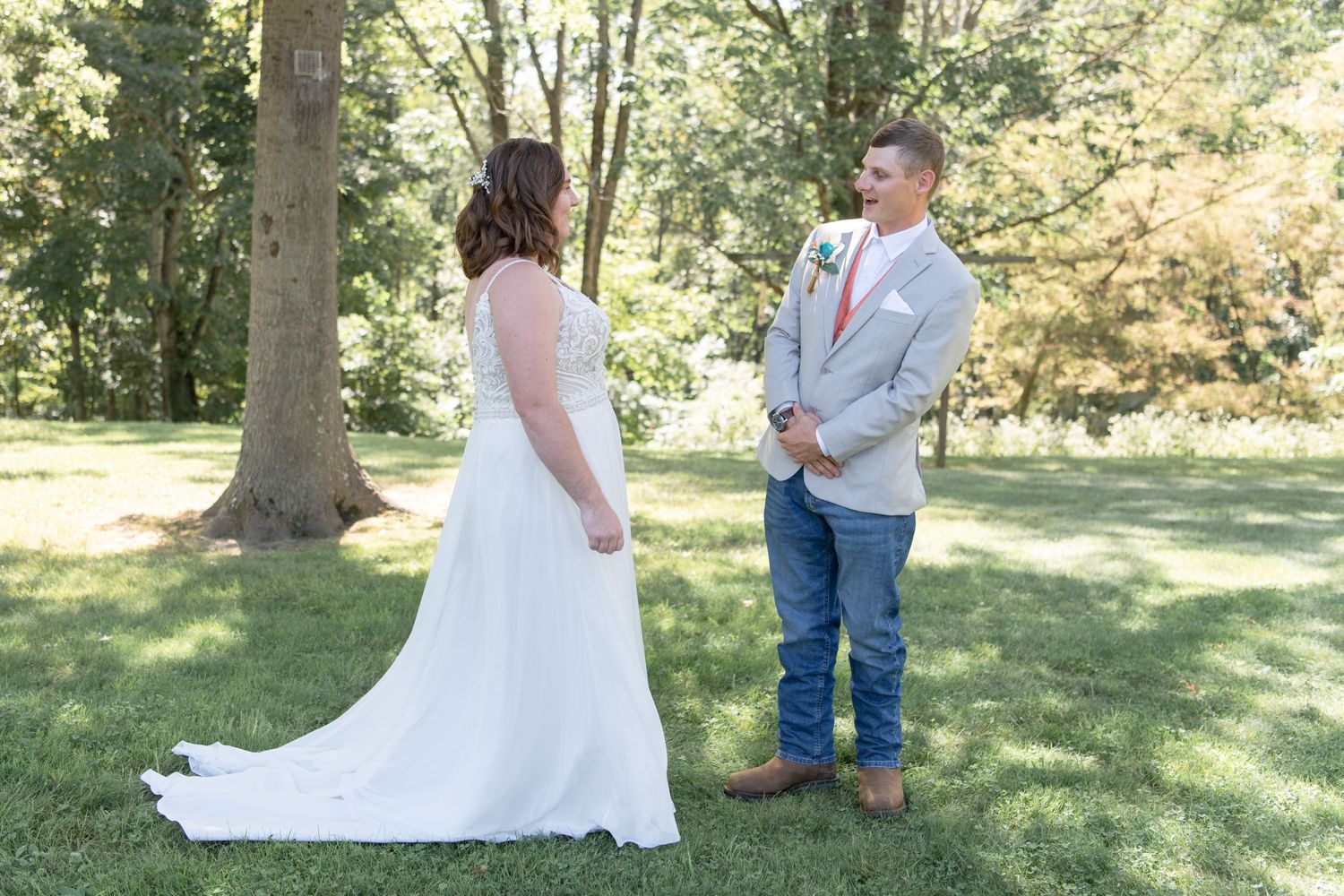 Outdoor wedding ceremony in natural woodland setting with white gown and casual attire.