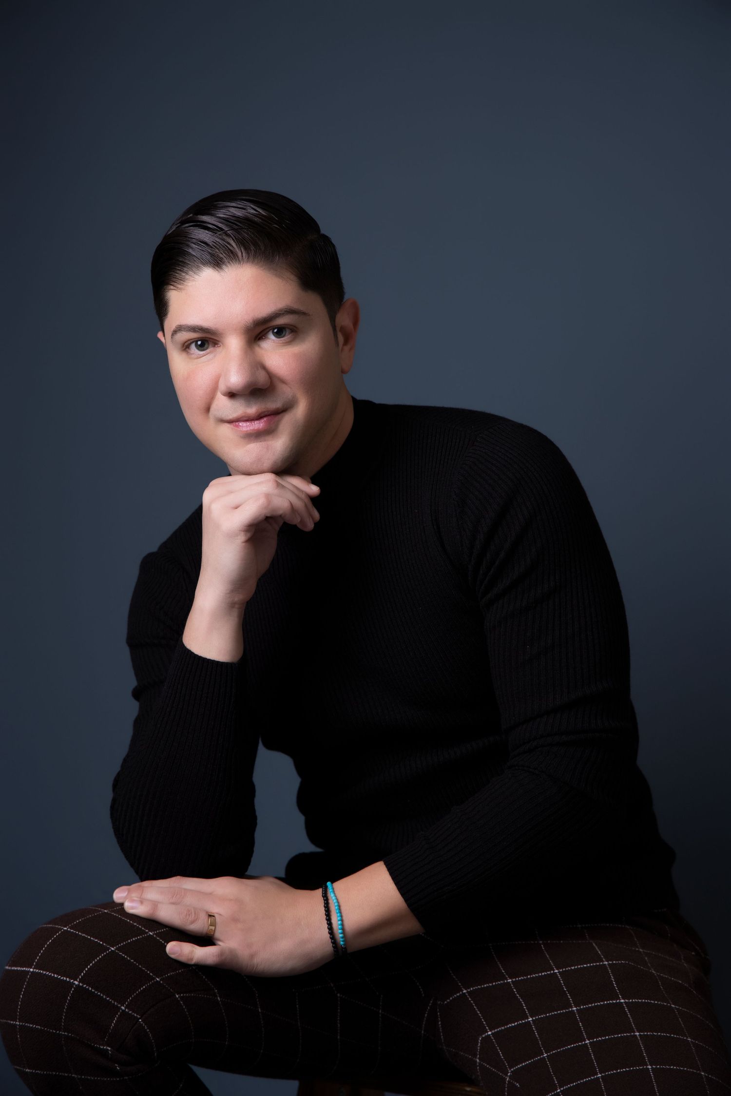 Professional studio portraits showing a person in a black sweater against dark background in various poses.