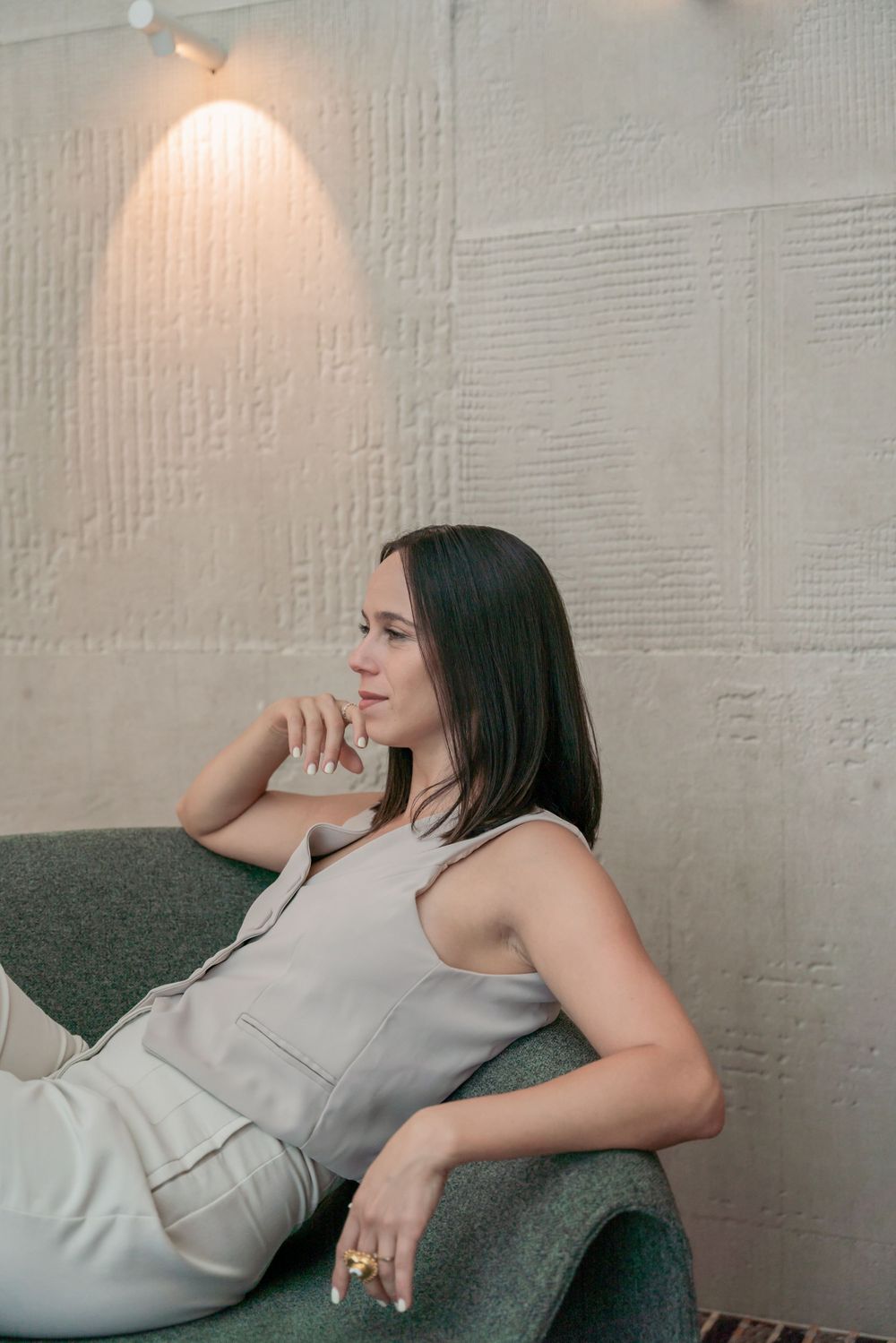 Modern lifestyle portrait of someone relaxing on grey couch against textured wall.