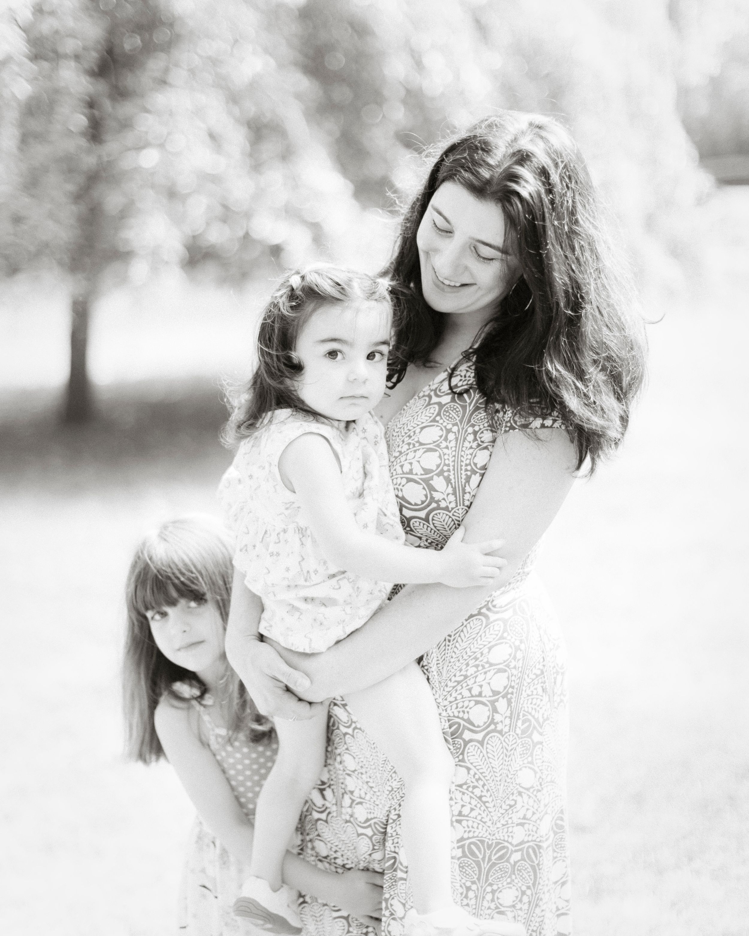 Intimate family portrait of mother and children in black and white outdoors.