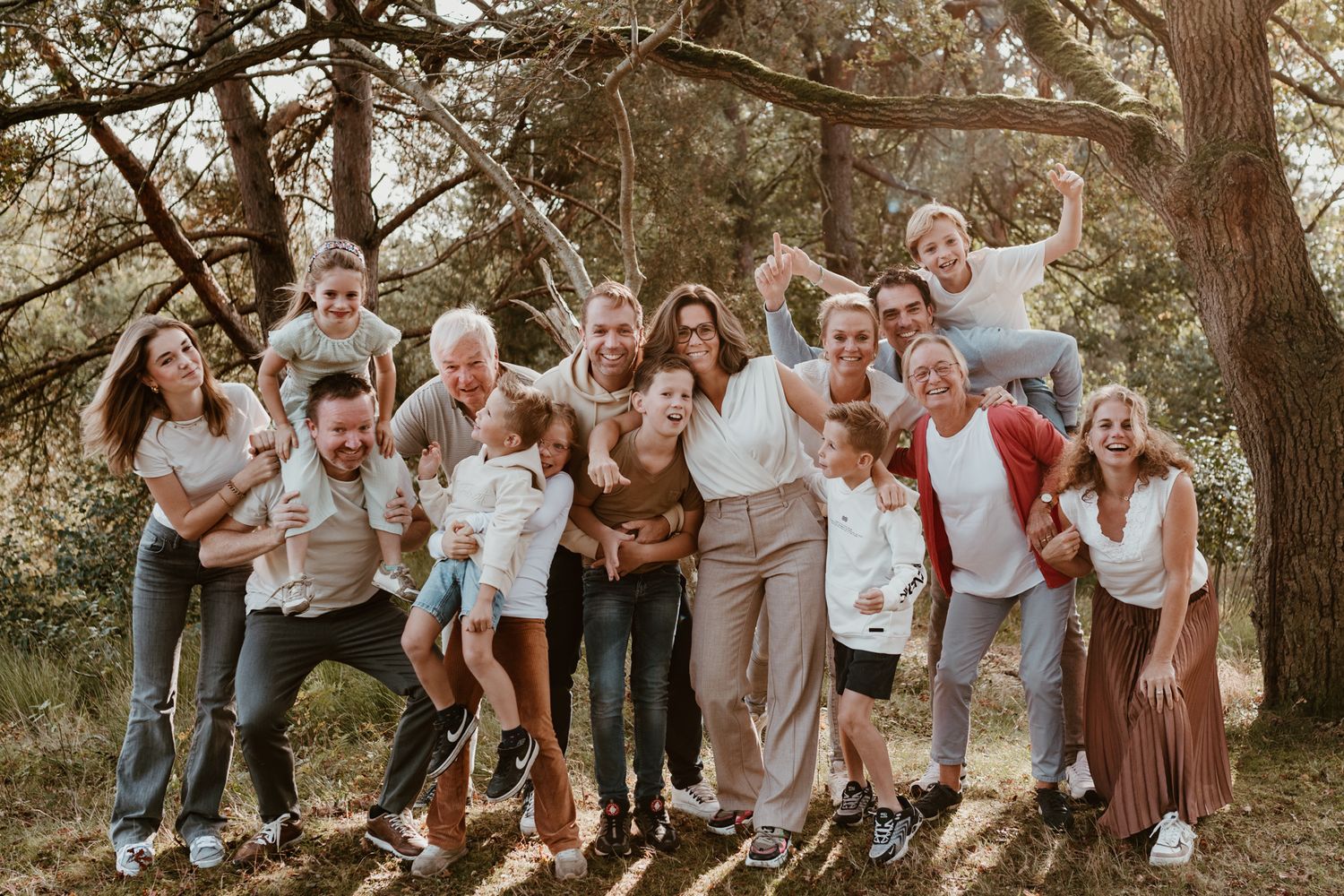 Grote groep familie poseert samen in een prachtige setting in het bos met mooi zonlicht door de bomen