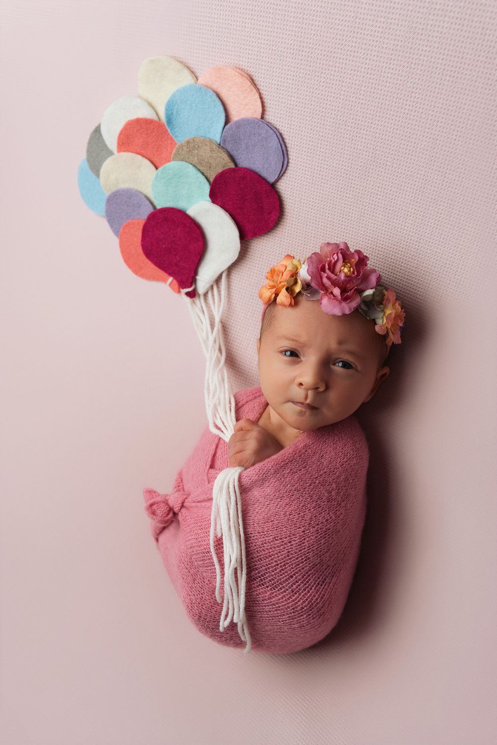 Newborn photography collage showing baby wrapped in pink fabric with colorful balloon props and floral headpiece.