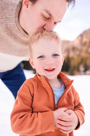 salt lake city utah family photographer, candid photo of a dad kissing toddler's head in snow