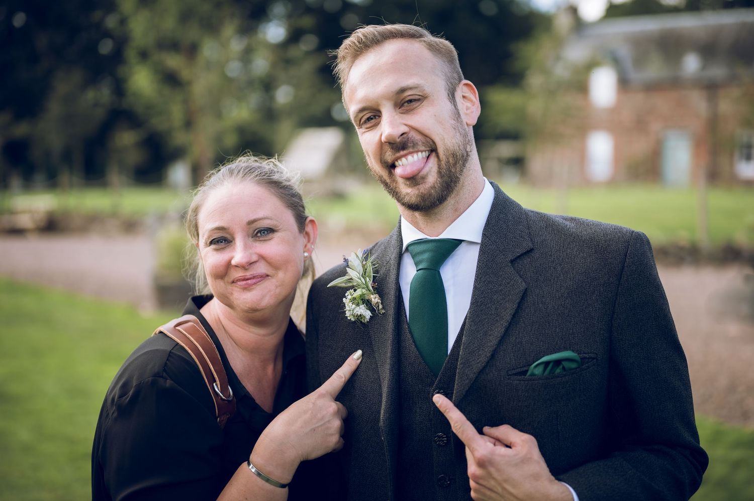 Professional photographer and wedding officiant pose together outdoors with matching expressions.
