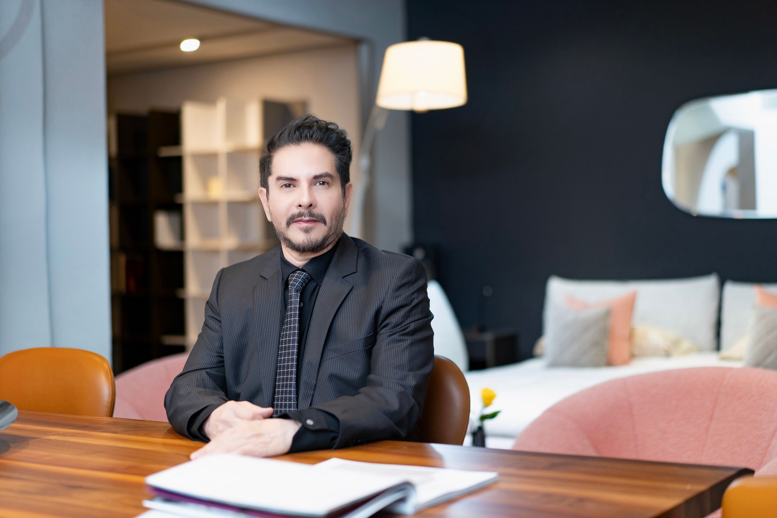 Retrato de arquitecto o diseñador sentado en mesa de madera dentro de showroom de mobiliario moderno
