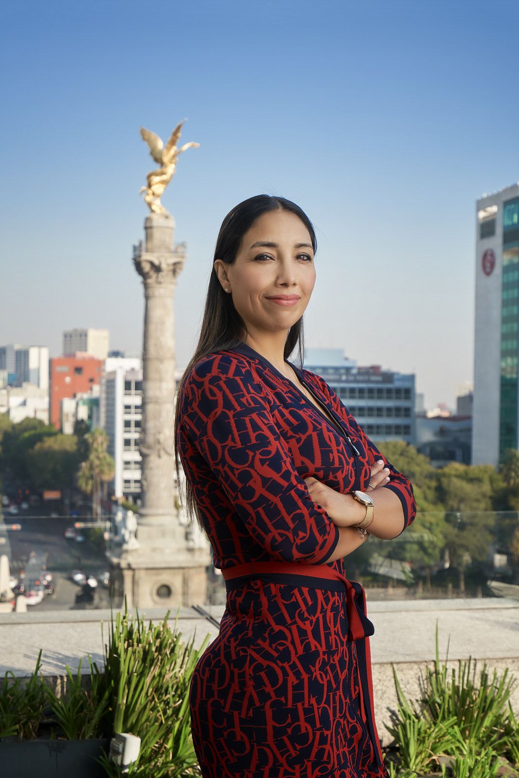 Ejecutiva posando en terraza de seguros Monterrey con el Ángel de la Independencia y edificios de Reforma al fondo.