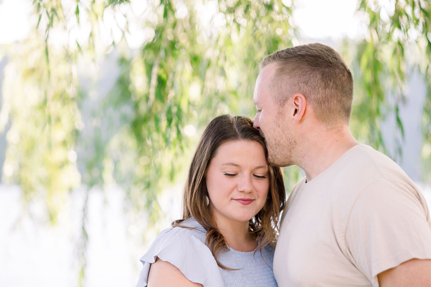 A tender moment shared under drooping willow tree branches.