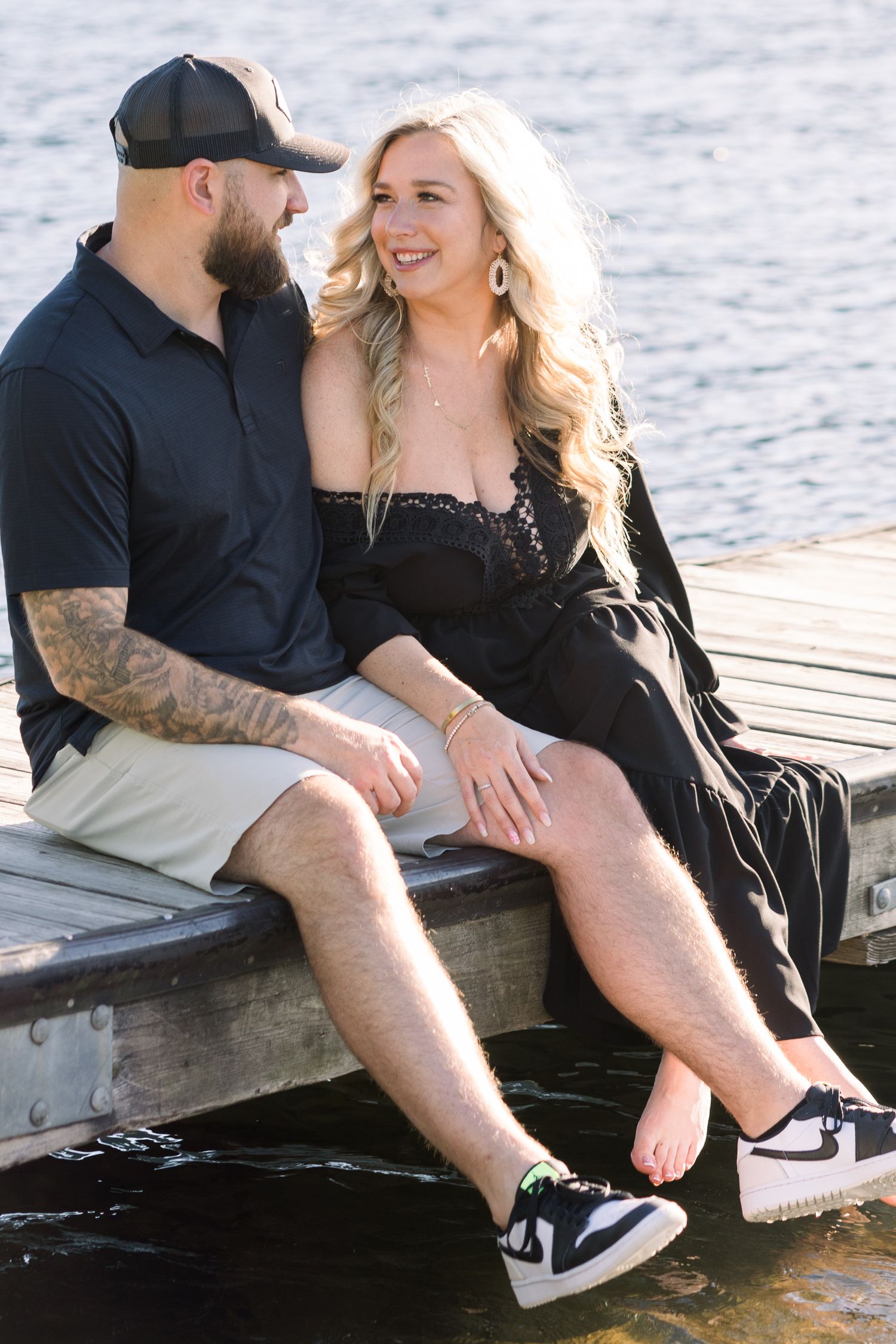 Couple sitting on wooden dock sharing intimate moments by the water.