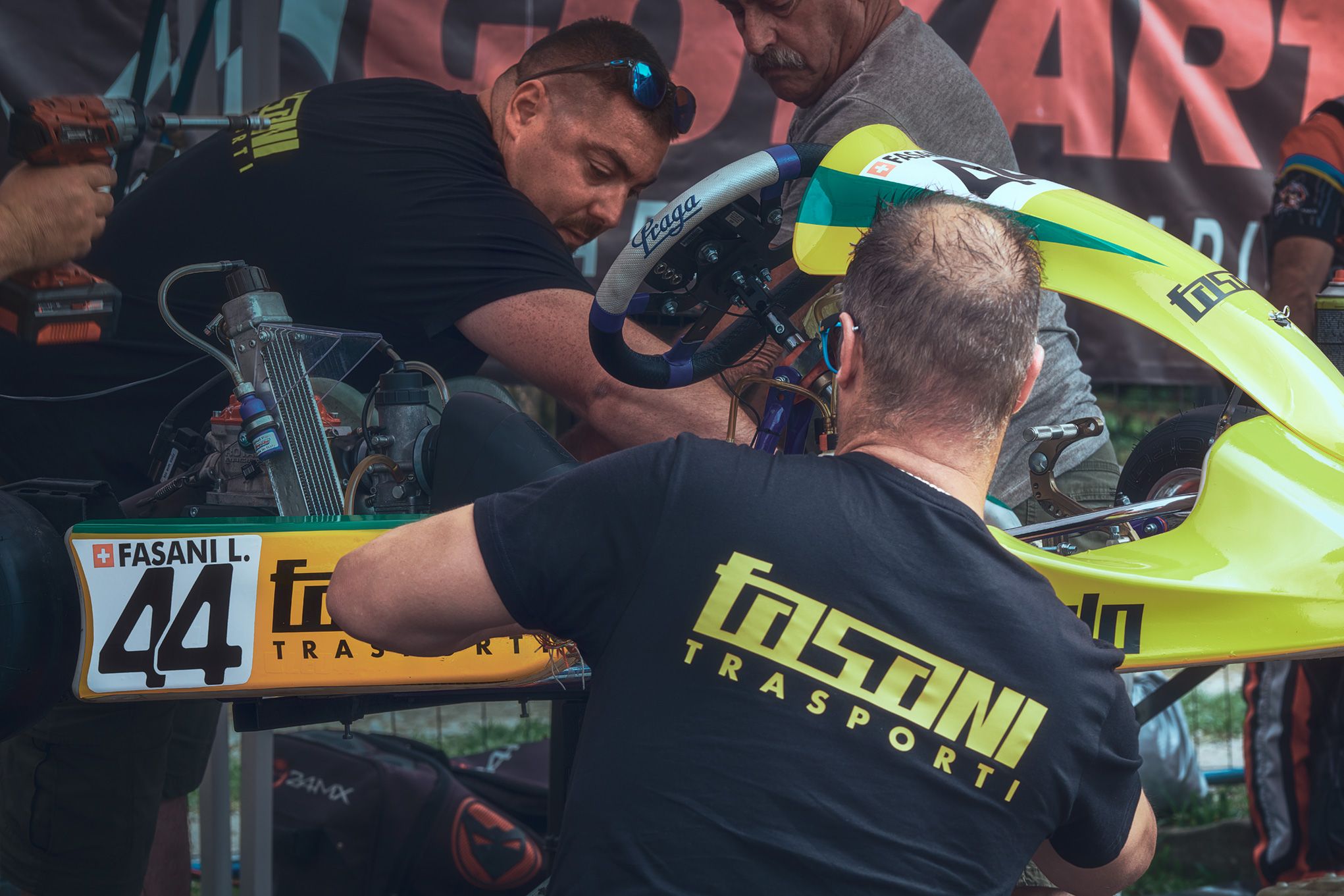 Manutenzione tecnica su kart da gara del pilota Fasani L. durante il Locarno Kart Trophy. Il team meccanico lavora con precisione sul kart