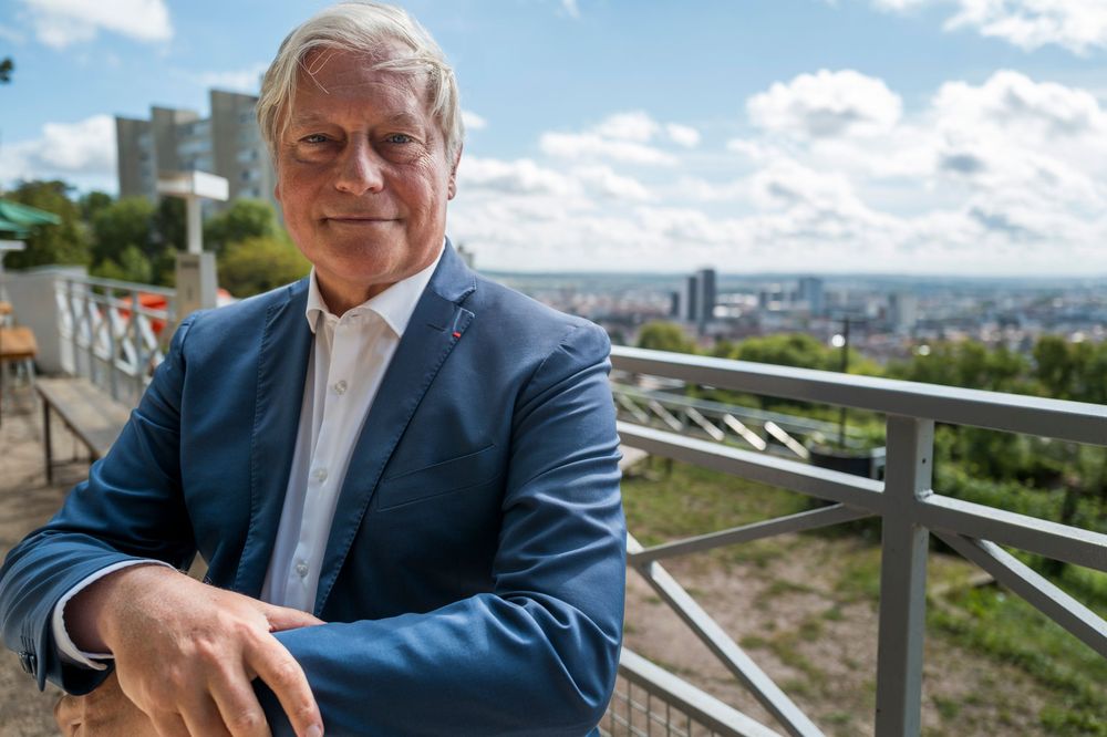 A business professional in a blue suit enjoys outdoor views from a scenic overlook on a sunny day.