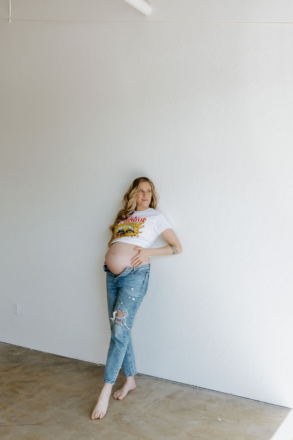 A sequence of minimalist photos showing someone in jeans and white shirt leaning against a white wall in different poses.