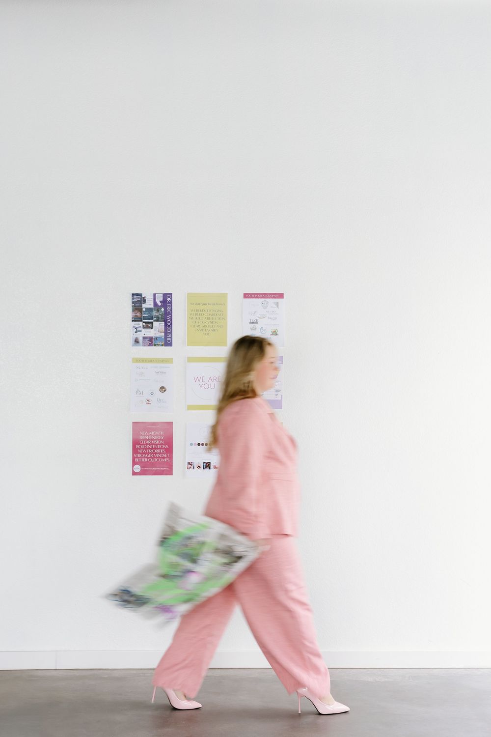 Person in pink scrubs walking past white wall with posted medical information.