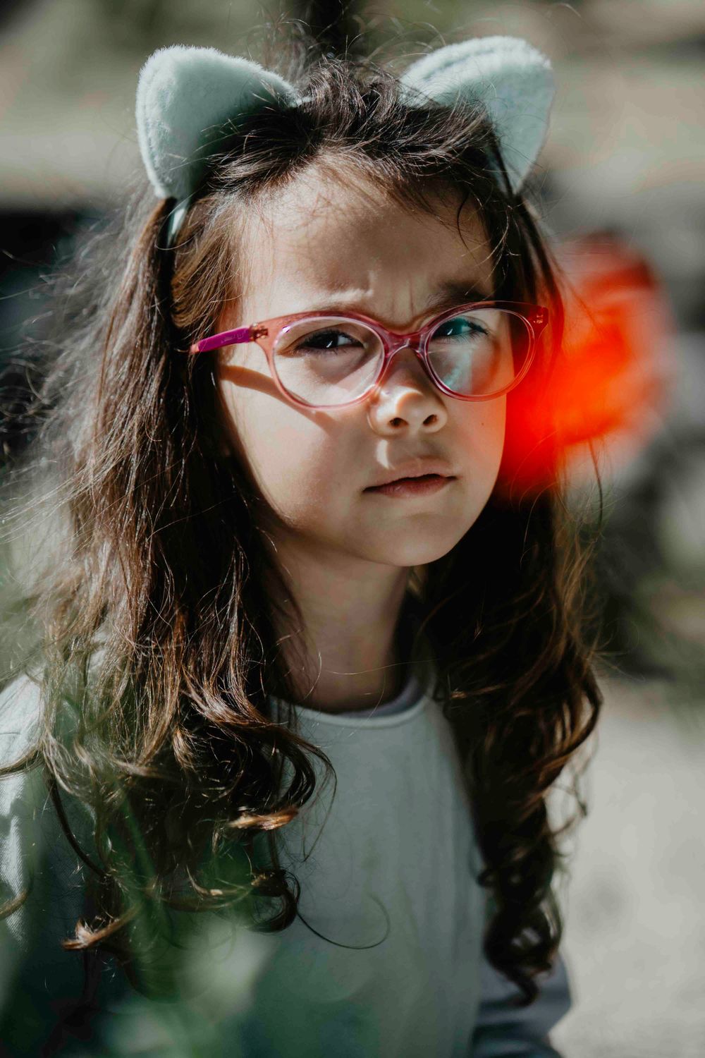 Retrato de uma menina com expressão serena,cercada por galhos ao ar livre, transmitindo naturalidade e doçura infantil em ambiente campestre