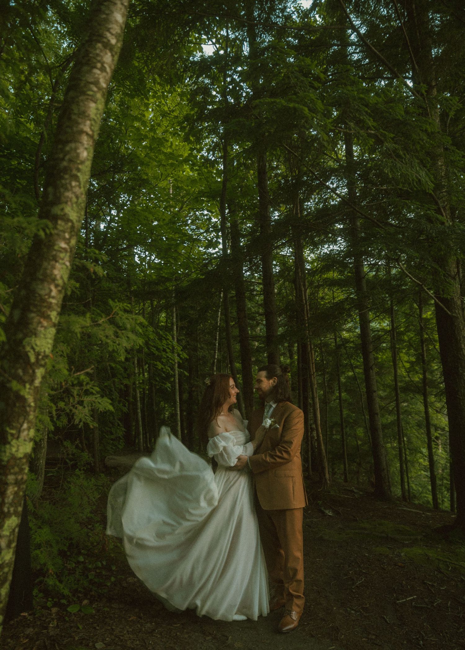 A romantic woodland photoshoot featuring a flowing white dress against a lush forest backdrop.