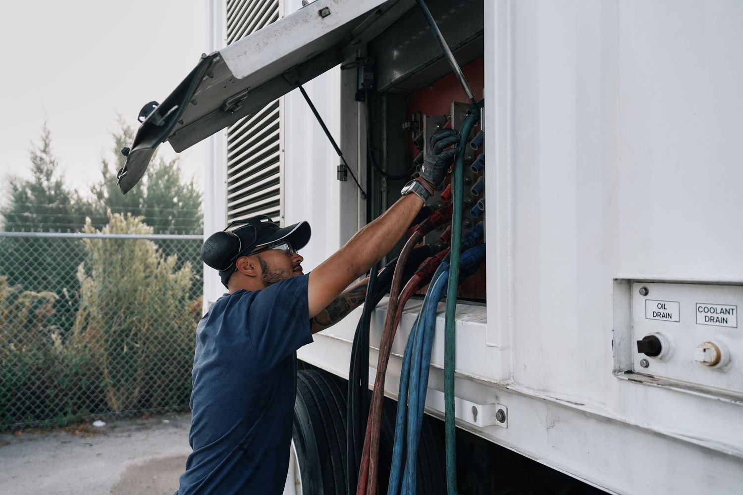 Worker in blue uniform adjusts equipment on industrial machinery.