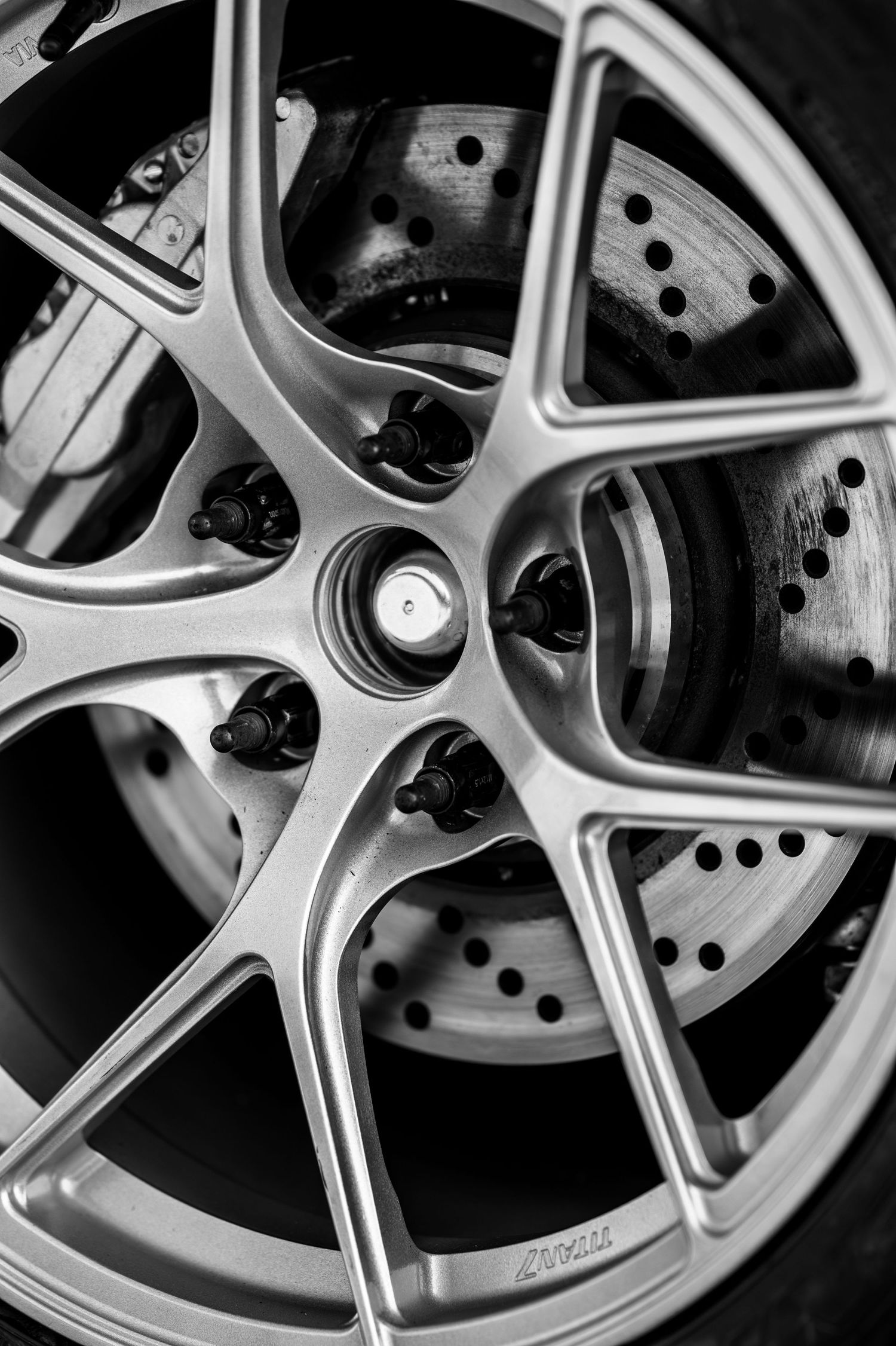 Close-up detail of silver sports car wheel rim and brake disc.