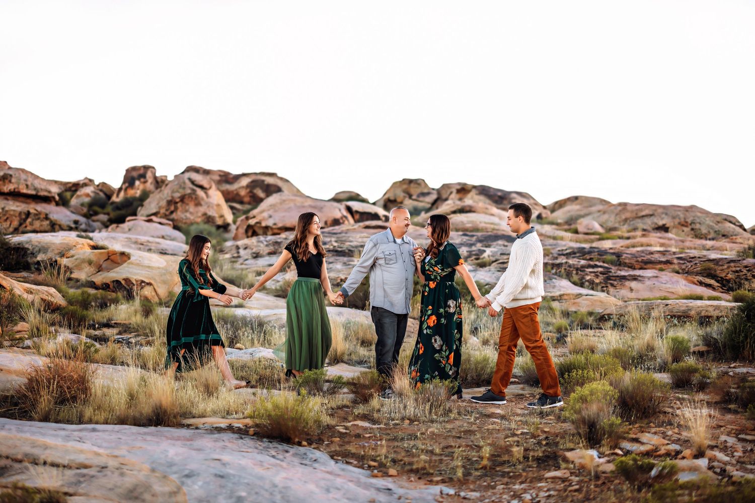 People in coordinated outfits walk together across scenic desert rock formations at sunset.