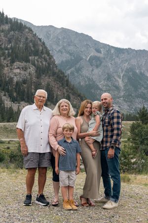 A family poses together against a stunning mountain landscape backdrop in the wilderness.