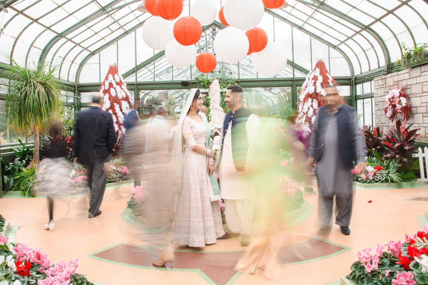 Greenhouse decorated with red paper lanterns and floral arrangements for a wedding celebration.