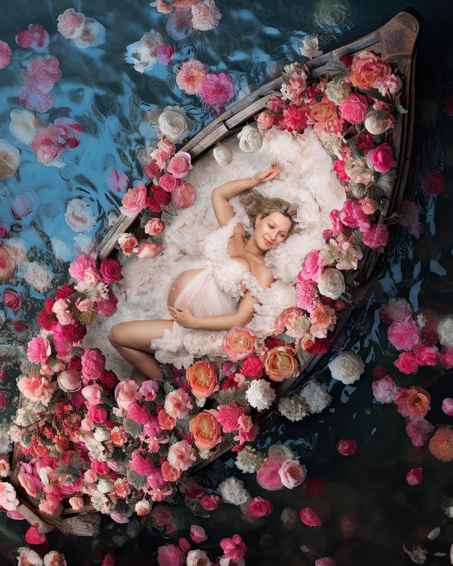 Sydney Maternity Photoshoot of a woman in a cream couture gown laying in boat floating on a river scattered with flowers