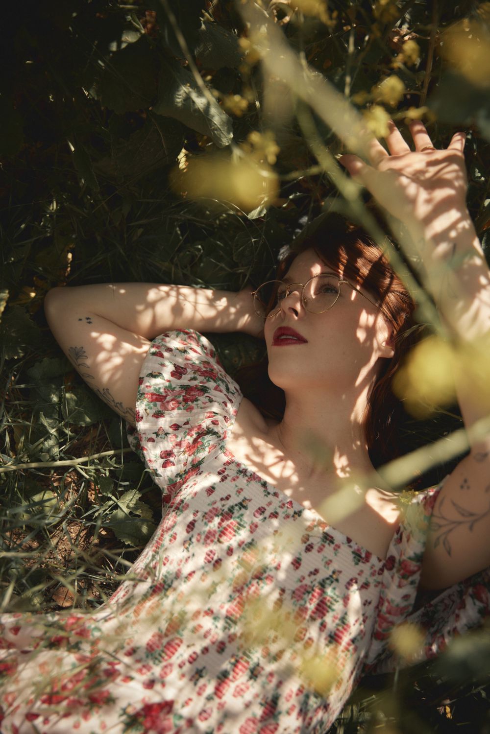 A romantic summer portrait with dappled sunlight through leaves and a floral dress.