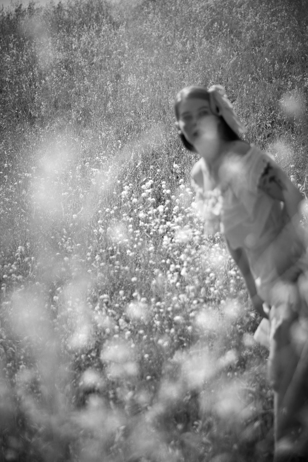 An ethereal black and white portrait of a figure dancing among wildflowers.