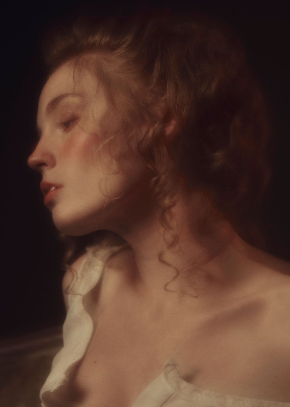 Artistic profile portrait with soft focus lighting creating romantic Renaissance-style aesthetic.