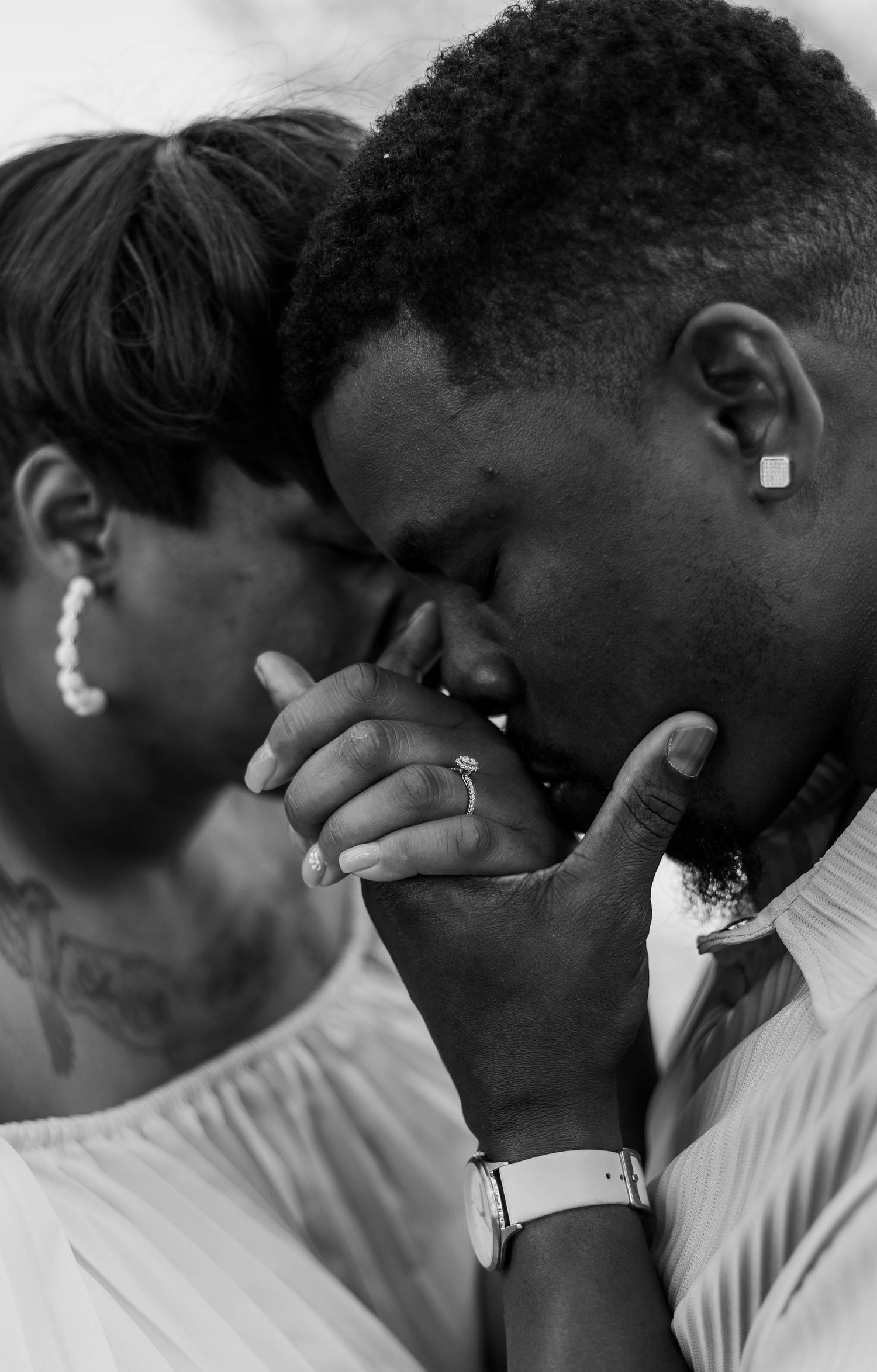 A tender black and white photograph showing an emotional moment between two people in white attire.