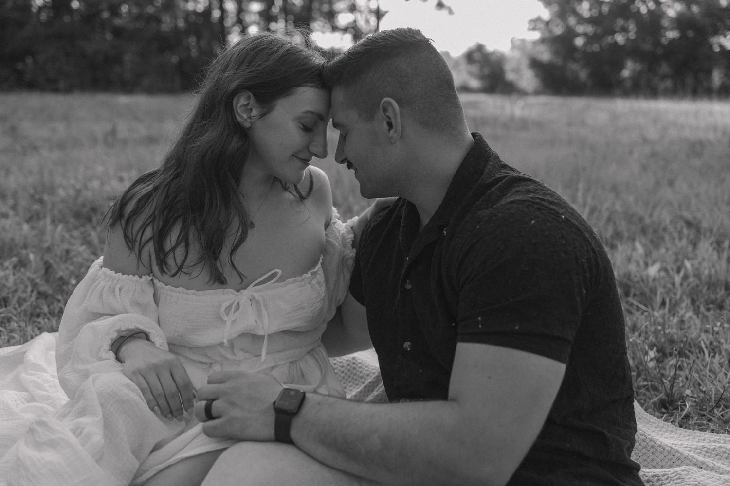 An intimate couple's portrait session in a grassy field during golden hour.