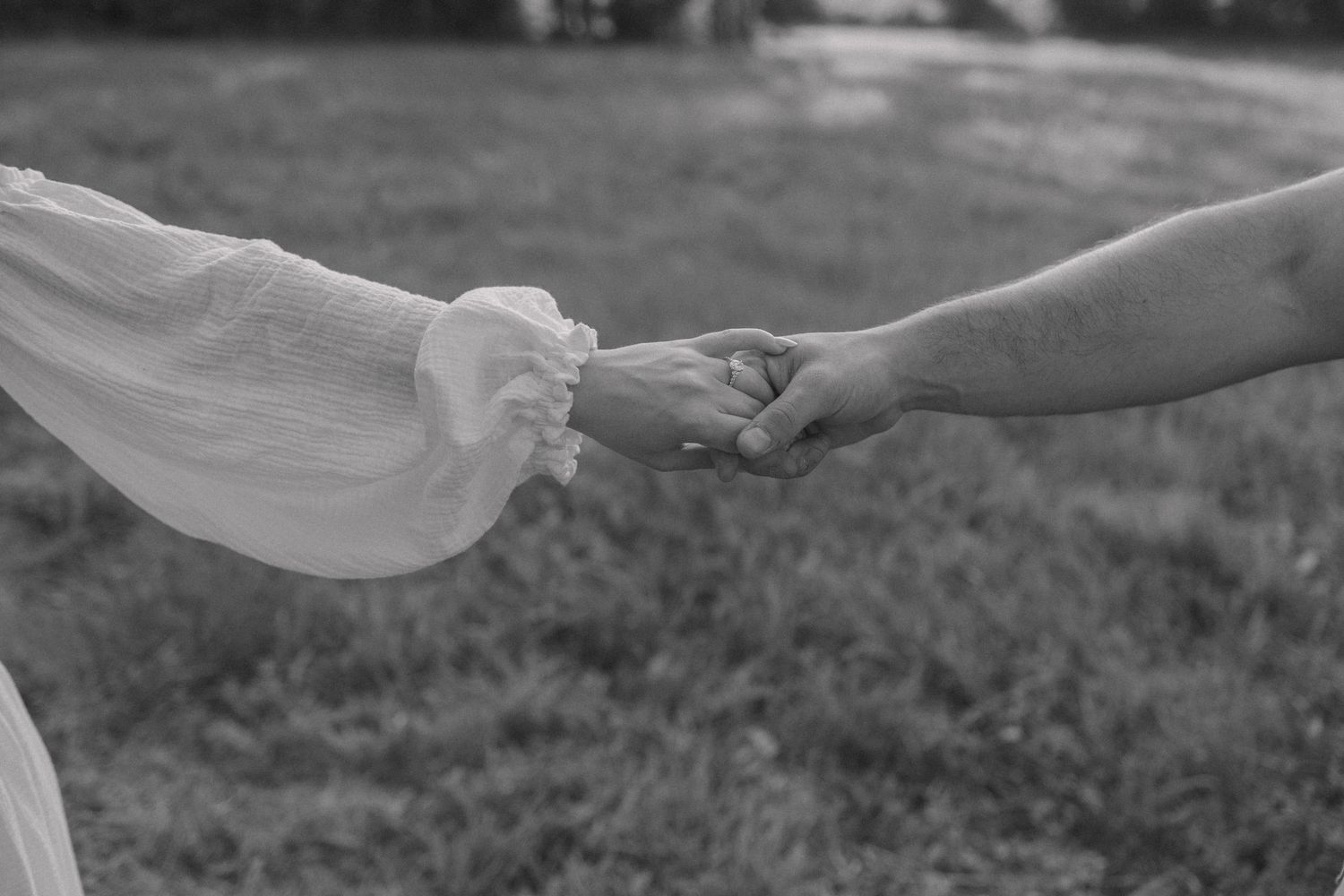 Close-up of hands reaching toward each other during an outdoor photo session.
