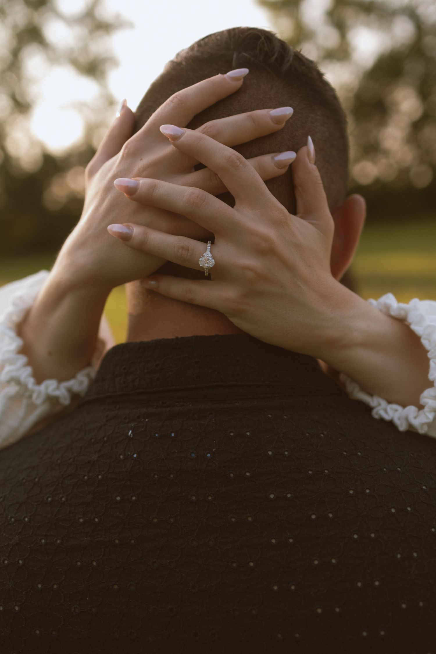 Close-up of hands with an engagement ring embracing during an intimate moment.