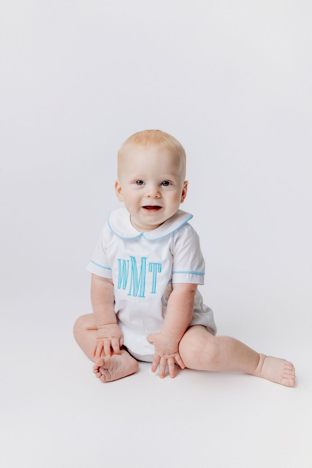 Baby wearing white and blue monogrammed outfit during studio Heirloom photoshoot.