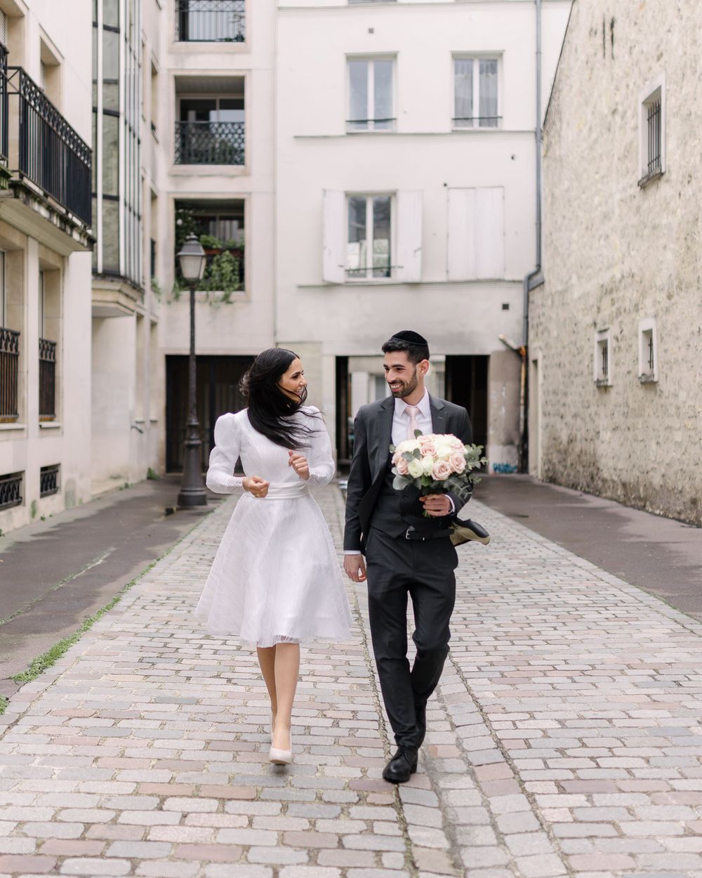 Couple walking together on a charming cobblestone street in Paris.