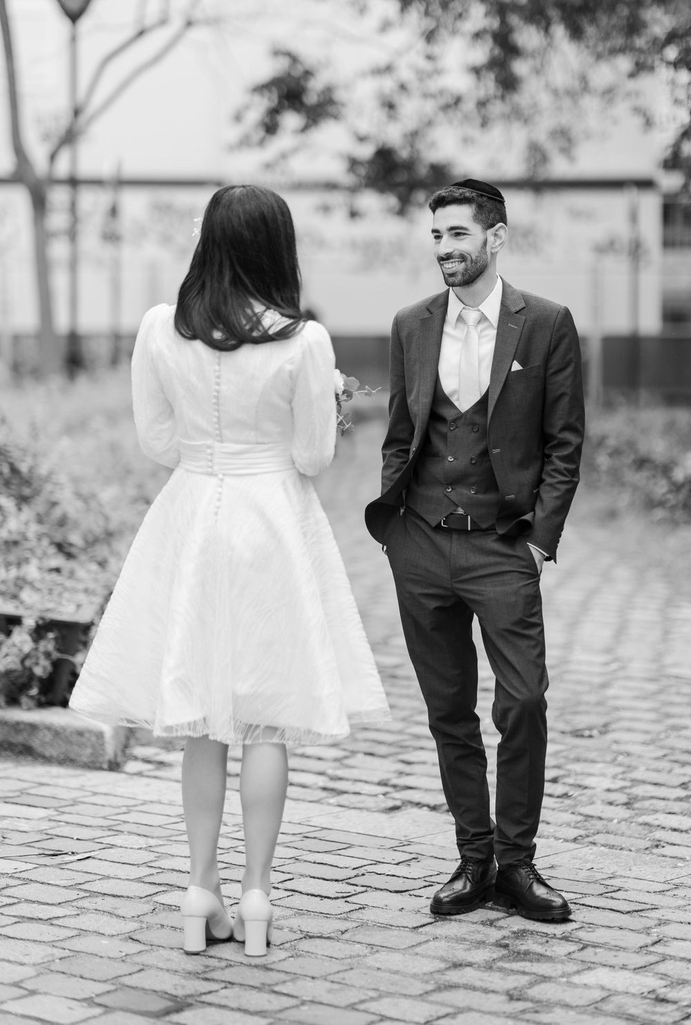 Romantic black and white photo of couple on cobblestone pathway.