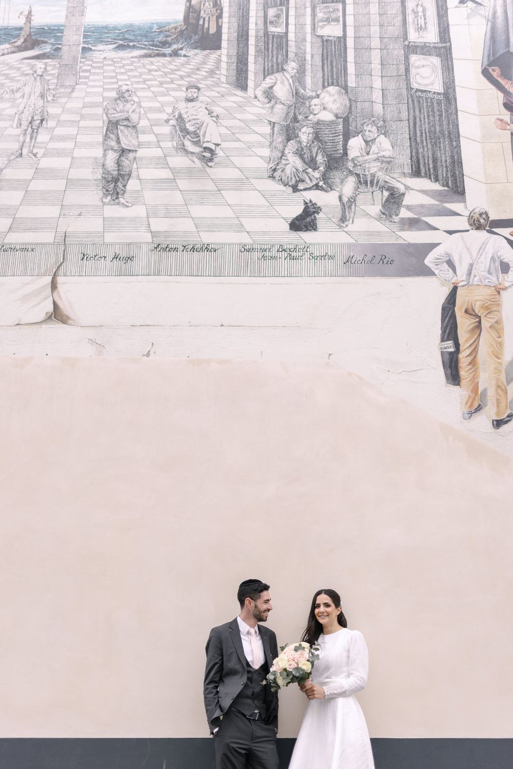 LOVING Couple posing against wall with vintage street scene mural.