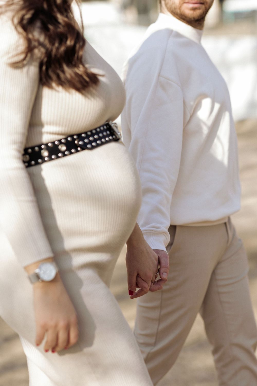 Couple in coordinated cream and white outfits with studded choker necklace posing together in romantic engagement photos.
