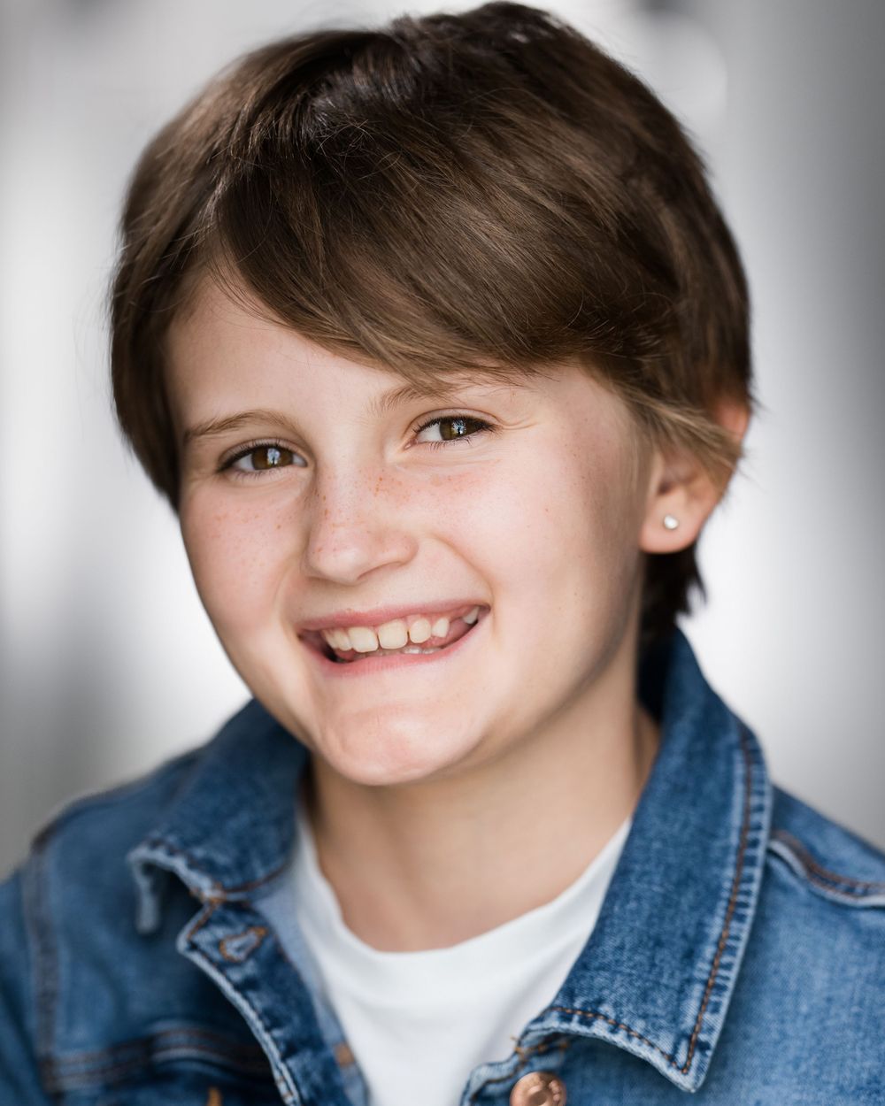 Professional headshot of youth wearing denim jacket and white shirt against light background in Guildford, Surrey.