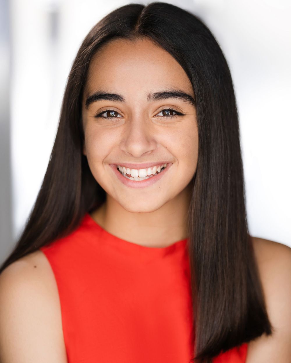 Professional headshot of smiling person with long dark hair wearing red top against light background in Guildford, Surrey.