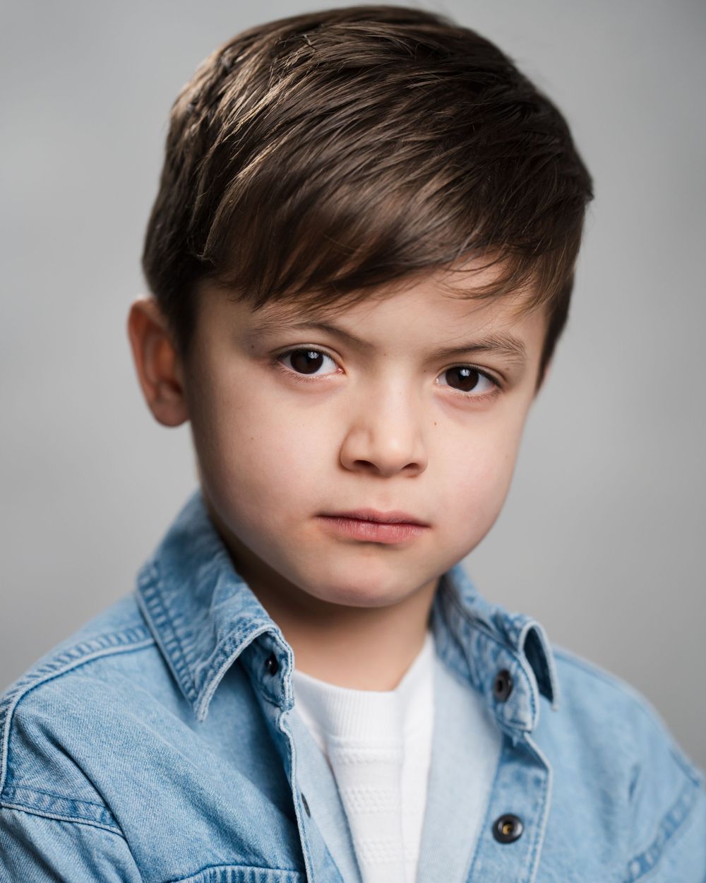 Studio headshot of young talent wearing denim shirt against grey background. Children's headshots Surrey.